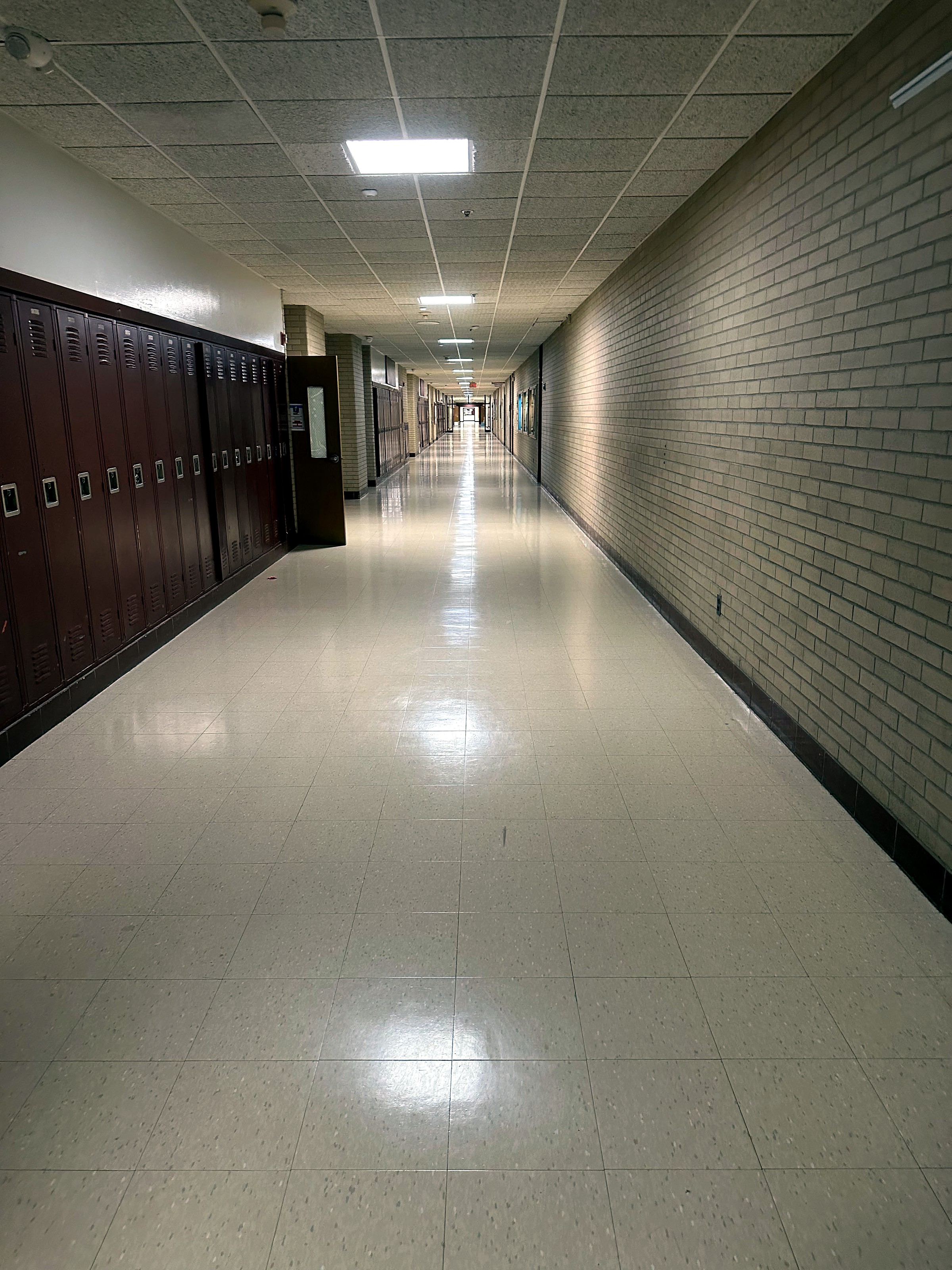 A school corridor with lockers and a freshly polished tile floor.